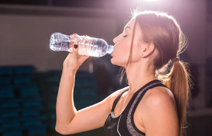 Frau die eine Flasche Wasser trinkt